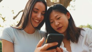 Young multi ethnic smiling women are watching videos on their phone